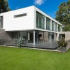 Charming White Details Dominate Impeccable Minimalist Home in Germany: Amazing Eco Friendly Home Architecture Equipped With White Walls And Stone Fence With Glass Window As Well As Spacious Green Yard