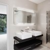 Charming White Details Dominate Impeccable Minimalist Home in Germany: Heated Towel Rail And Double White Washbasin On Black Wooden Table Adorn Modern Bathroom Design With Square Mirror On The Wall