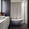 Bewitching Iron Lace Mansion in Canada Showcases Black-Dotted Staircase: Black And White Interior Design Bathroom Equipped With Contemporary White Bathtub And Modern Bathroom Vanity
