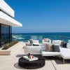 Breathtaking Contemporary Beach House with Perfect Architecture: Modern Patio Furniture With White Sofa And Black Round Coffee Table As Well As Glass Railing With Beach Scenery
